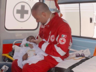 Un travailleur de la Croix-Rouge costaricienne berce un nourrisson à l’intérieur d’une ambulance, symbole de compassion et d’aide humanitaire.