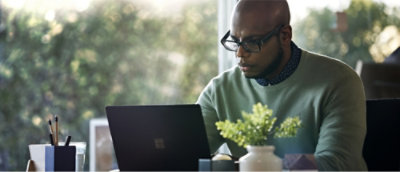 A man wearing glasses looking at a laptop.