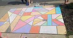 two children are standing on the sidewalk with their feet up and one child is drawing