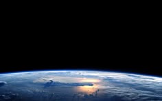 the sun is setting over the earth as seen from space