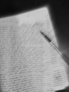 a black and white photo of a pen on top of a book with writing all over it