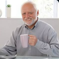 a man sitting at a desk holding a coffee cup