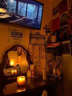 a room with a television, candles and pictures on the wall above it in front of a mirror