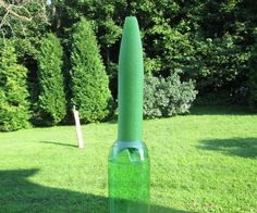 a green bottle sitting on top of a lush green field