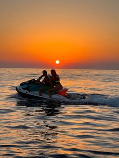 two people on a jet ski in the ocean at sunset