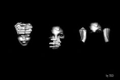 four people with hands covering their faces in the dark