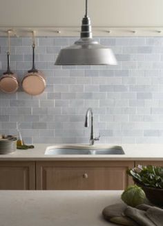 a kitchen counter with pots and pans hanging from the hooks on the wall above it