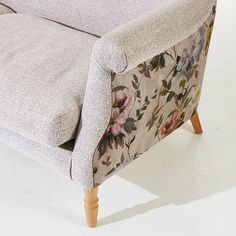 a couch with floral fabric and wooden legs
