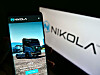 Person holding mobile phone with web page of US electric vehicle company Nikola Corp. on screen in front of logo.