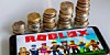 Roblox on a mobile phone, beside piles of coins