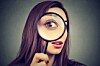 Curious woman looking through a magnifying glass