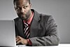 Man looks suspiciously over his shoulder while working on laptop. Photo via Shutterstock