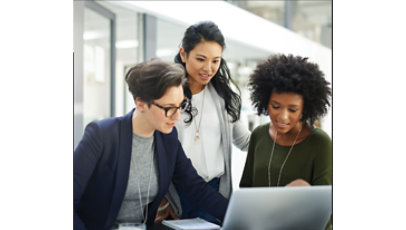 A group of three women looking at a laptop and having a discussion.