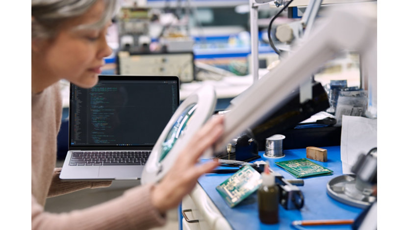 Computer science researcher inspecting CPU board through magnifier.