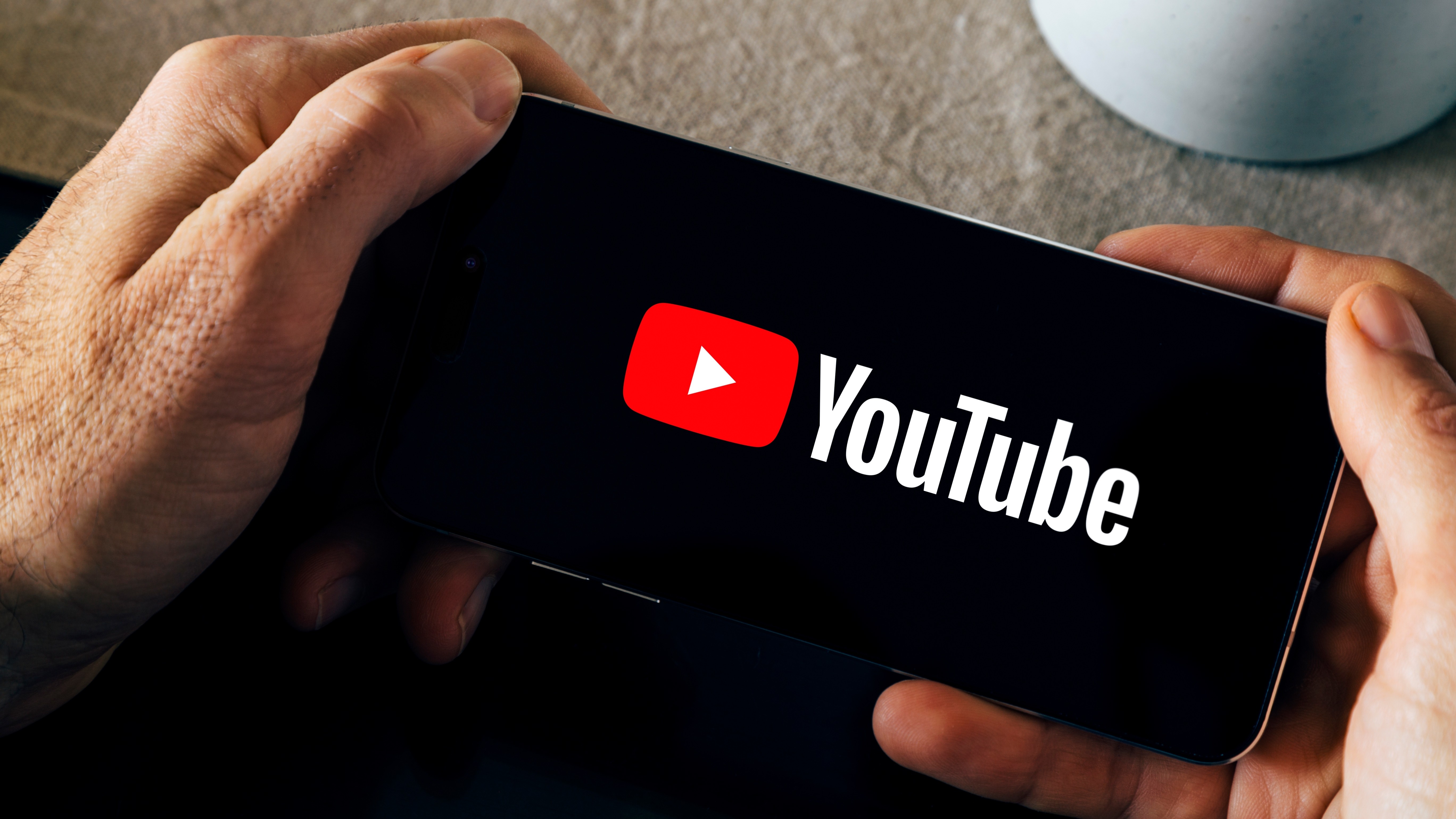 Man holding a smartphone with the YouTube app opening