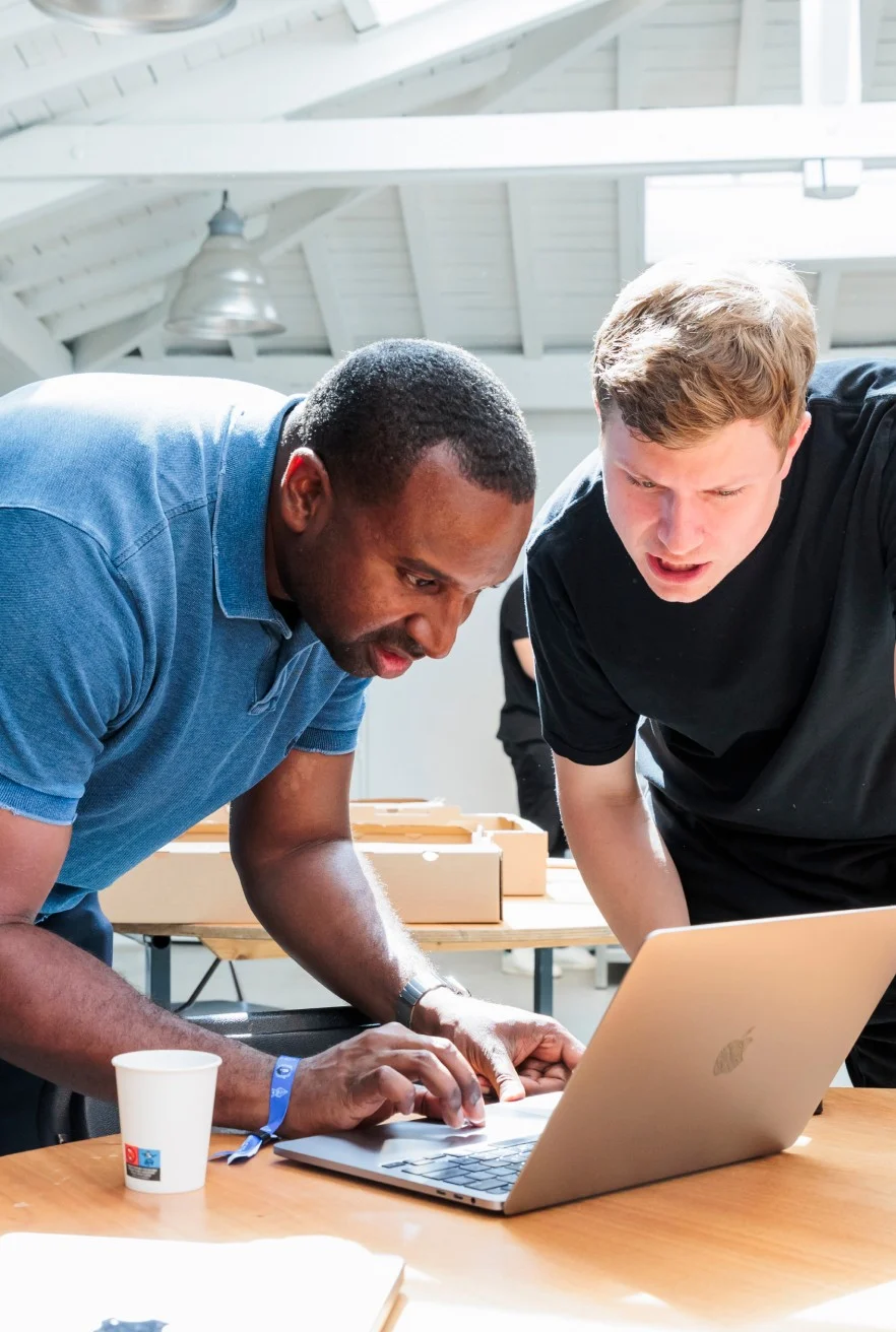 Two people standing behind a table while looking at a laptop