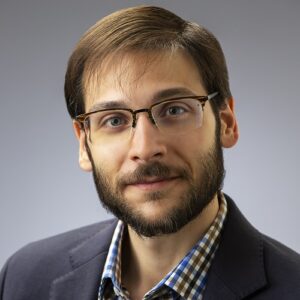A photo of Dominic DiFranzo (he/him). He is smiling at the camera and wearing a blue blazer and a button up shirt.