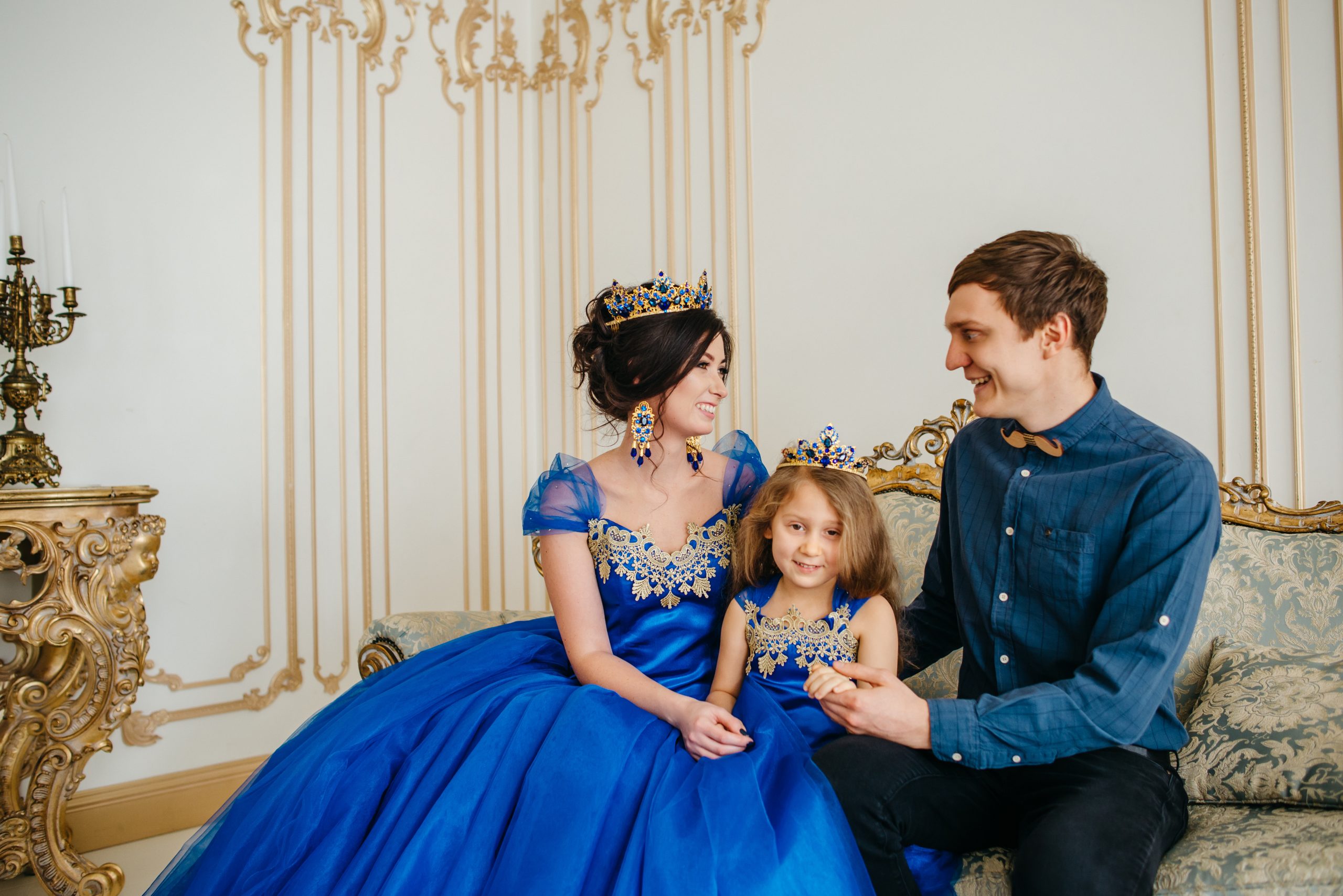 happy young family consisting of mother, father and little daughter in royal attire