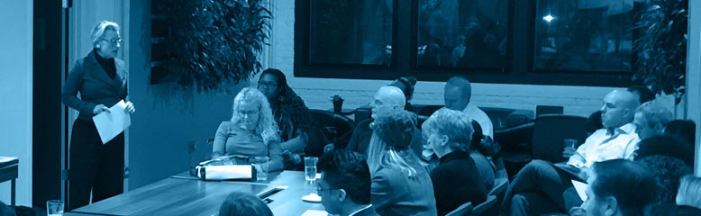 Filtered Photo of woman presenting to a table of listeners