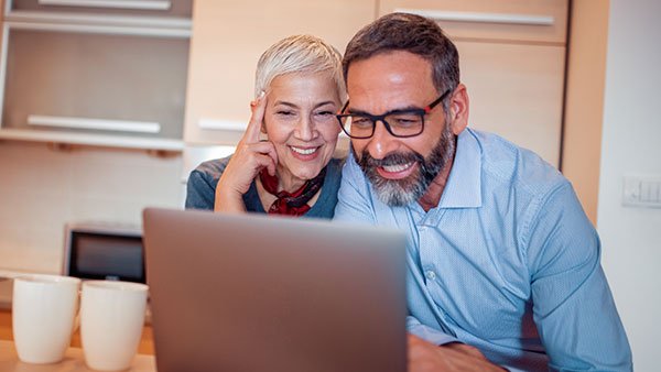Woman next to a man smiling when seeing something on a computer screen