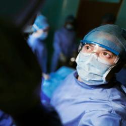 Doctor wearing mask staring into lamp