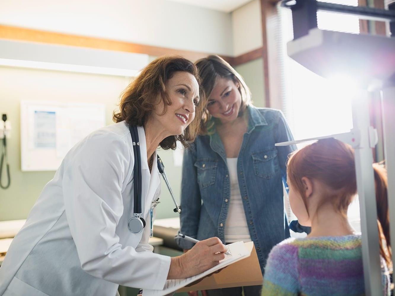 Doctor checking height of girl in examination room